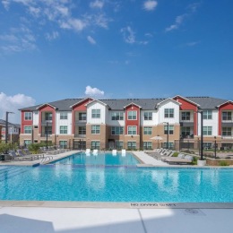 Our resort-style pool offers a refreshing and relaxing place to escape the heat for the day. How often will you be hanging out here? swimming pool with lounge chairs and a large building in the background